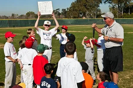A coach talking through a play with a circle of campers