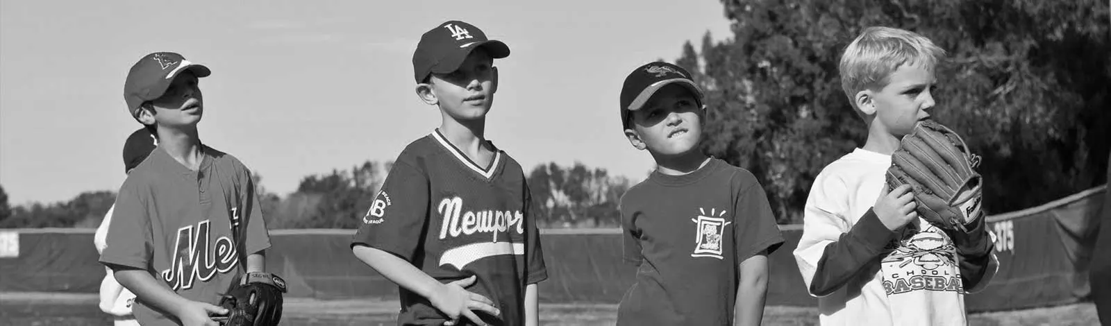 Four young Cresse campers with gloves standing in a row on the field, in black and white